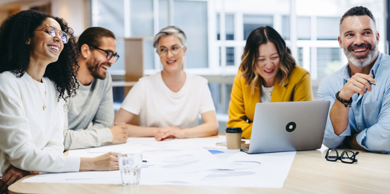 Smiling, diverse group of business people sitting at desk with laptop